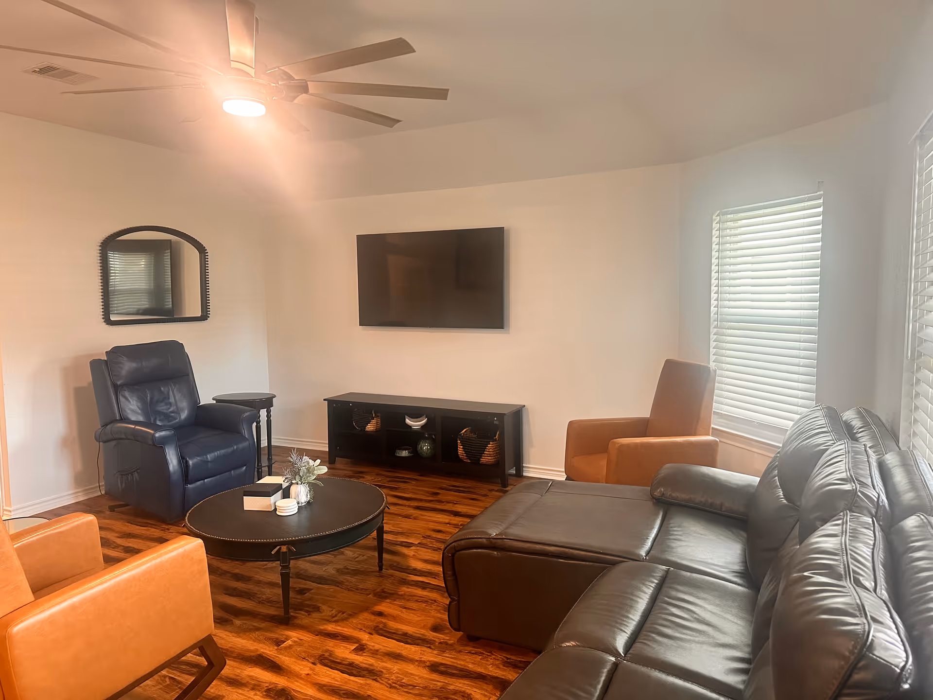 Cozy living room with leather sectional sofa, recliner, coffee table, and mounted TV.