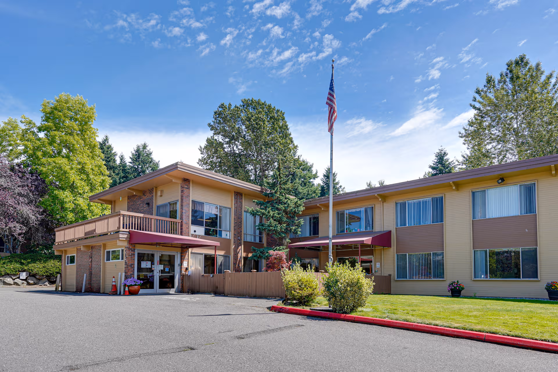 Exterior view of a two-story senior living facility with entrance and flagpole.