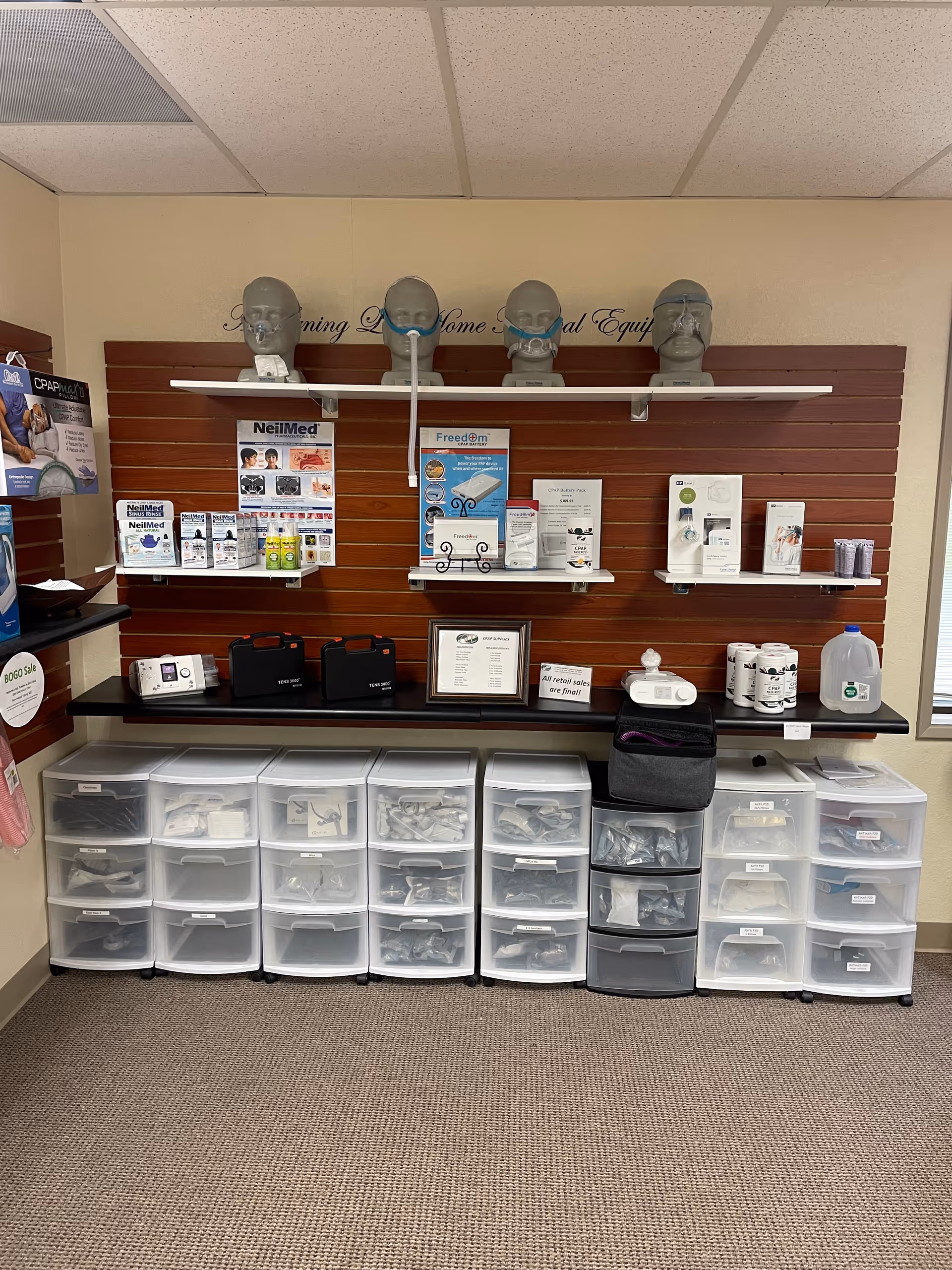 Interior medical supply display in a facility hallway with brochures, mannequins, and clear drawers.