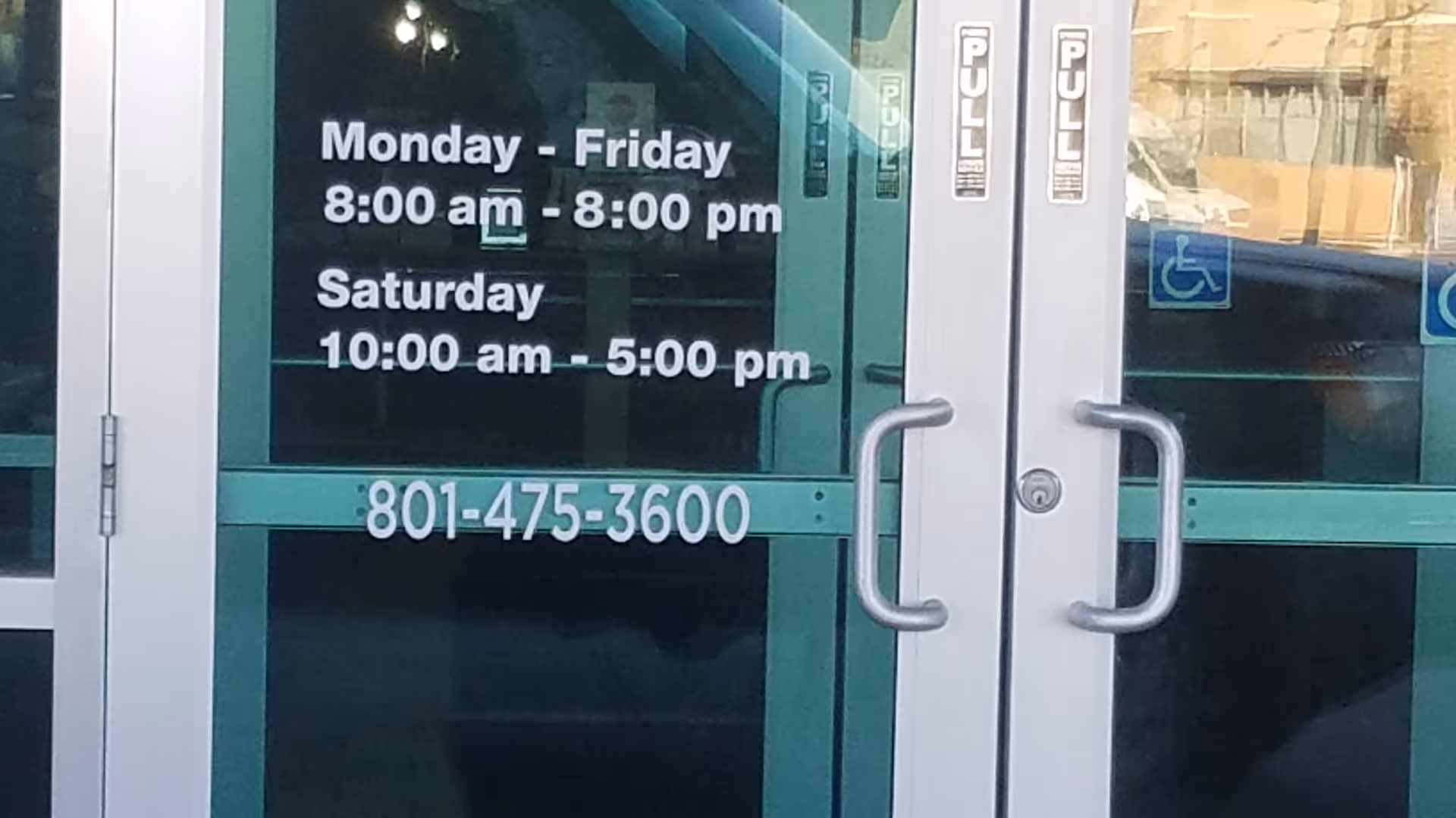 Glass entrance doors display hours and phone number for Ogden Clinic Mountain View.