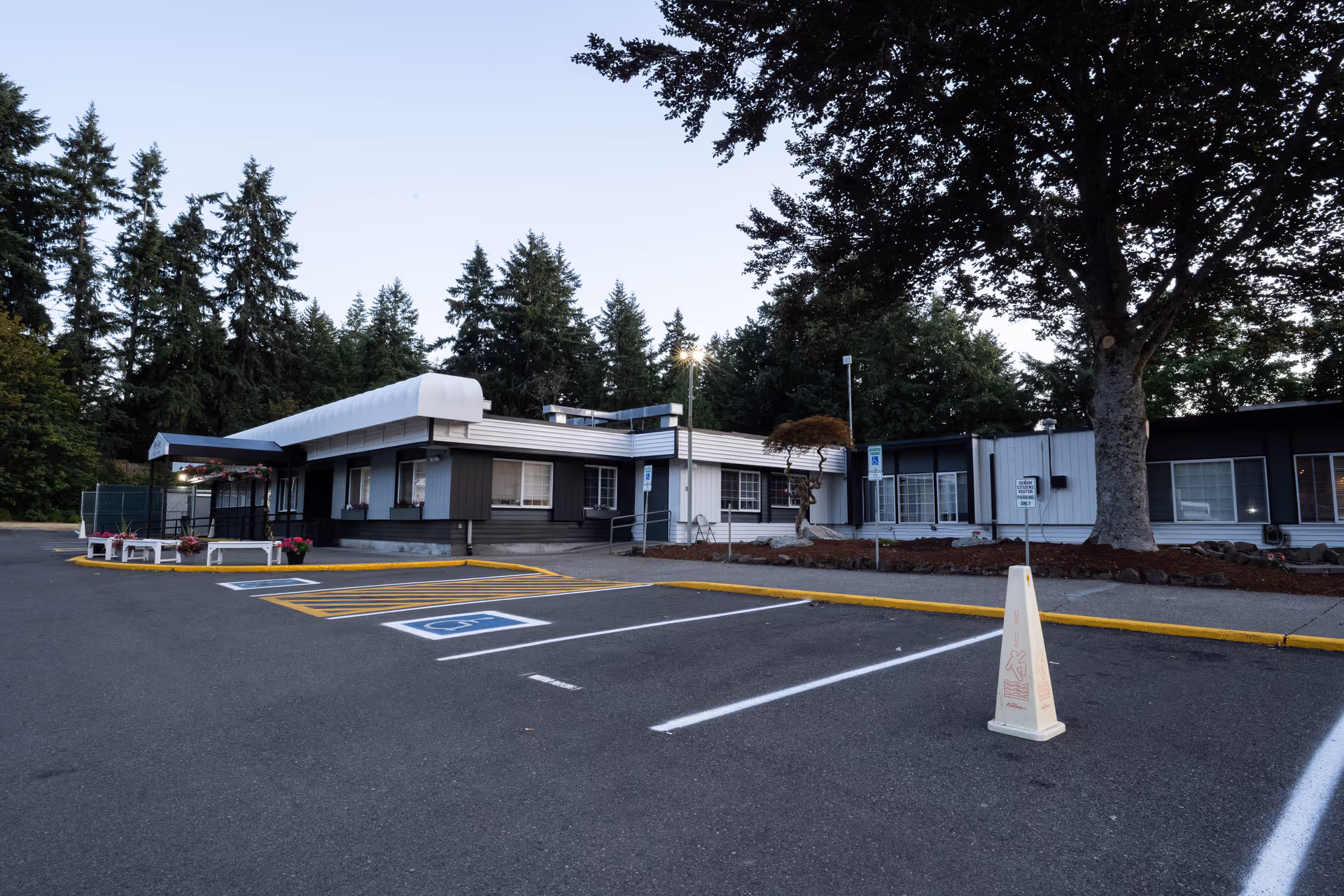 Exterior view of The Lodge at Roo Lan, a senior living facility, with parking and trees.