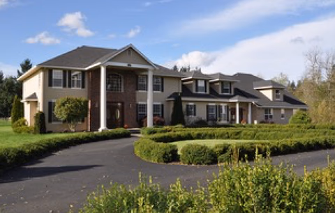 Two-story senior living facility with brick facade, driveway, and manicured hedges.