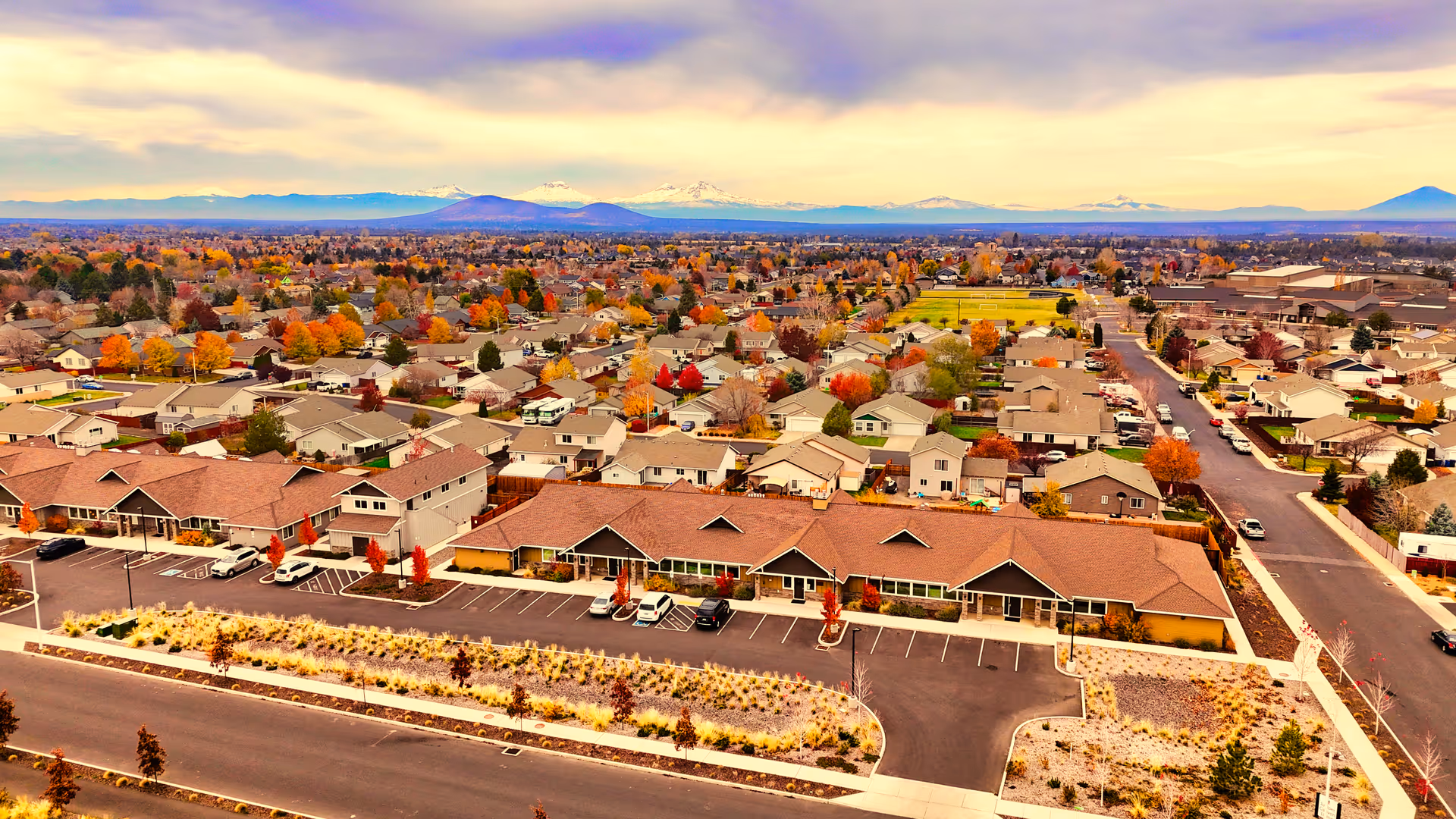Aerial view of Juniper Canyon Living senior facility with parking and surrounding neighborhood and mountains.
