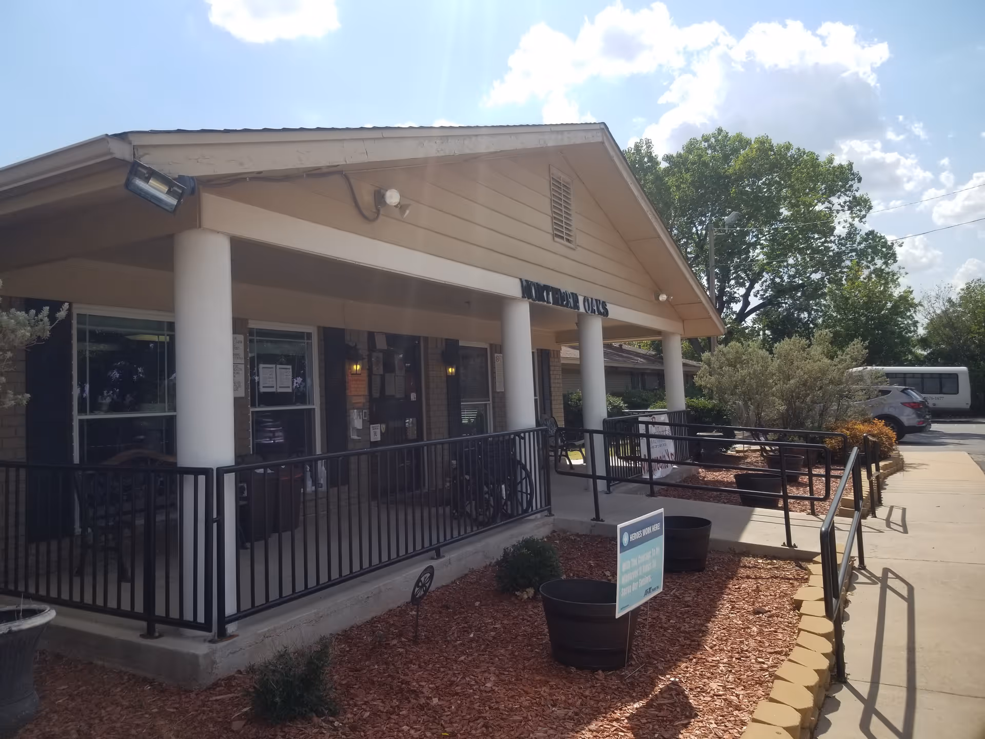 Exterior view of Northern Oaks Living and Rehabilitation Center front entrance with porch, railing, landscaping.
