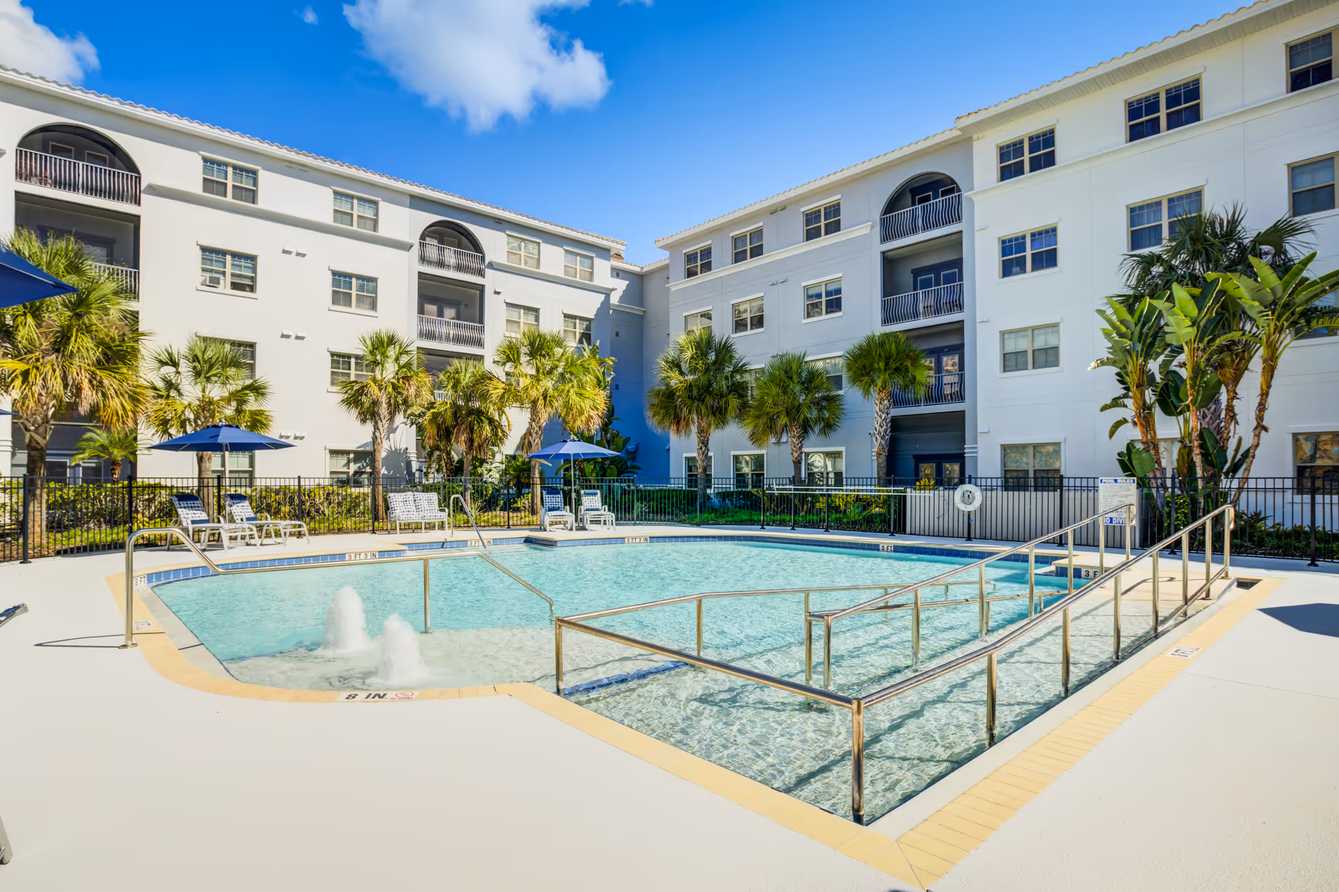 Sunny courtyard of Merrill Gardens at Solivita Marketplace with a swimming pool and palm trees.
