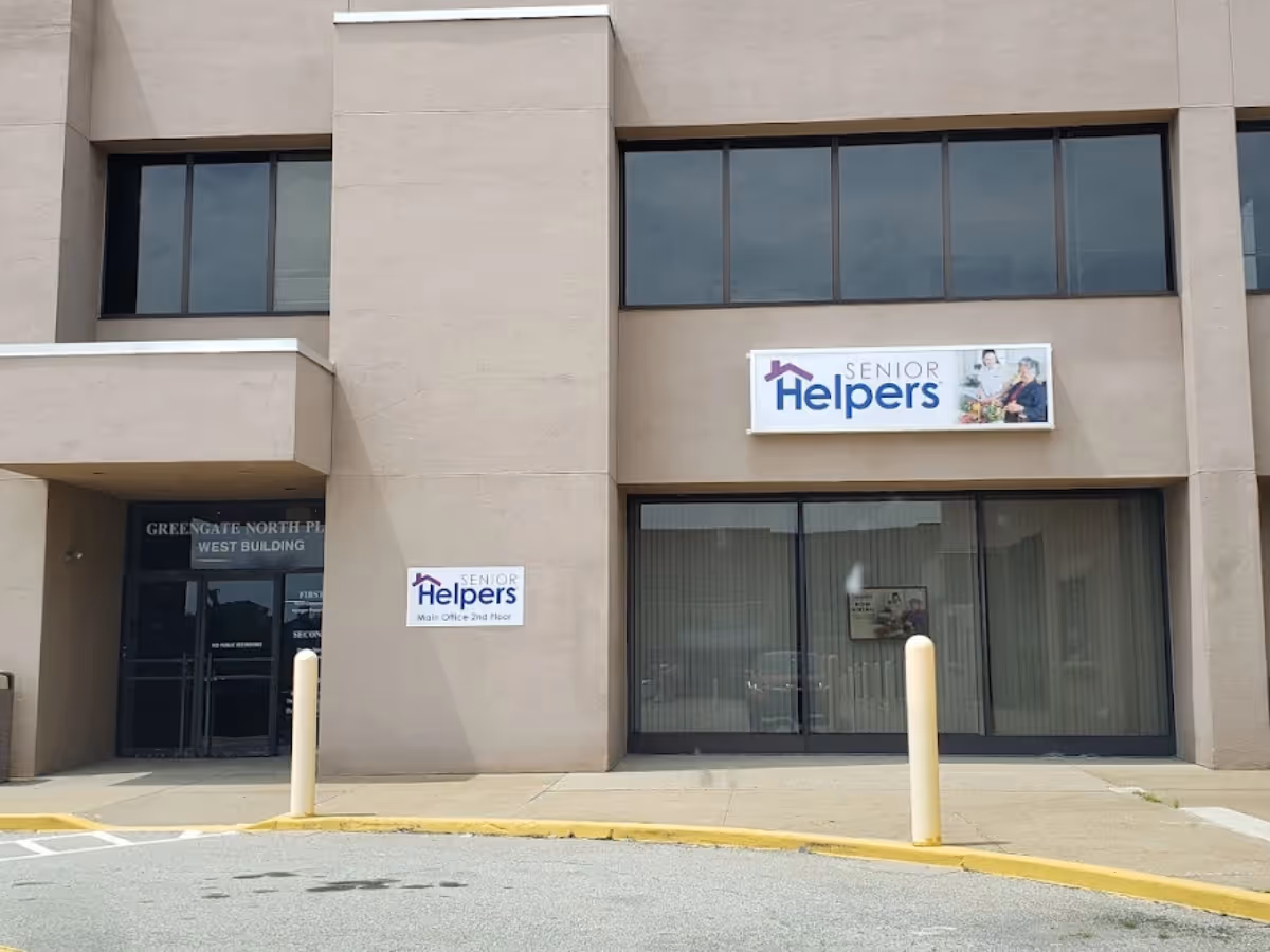 Beige building exterior with large windows and Senior Helpers sign above entry.