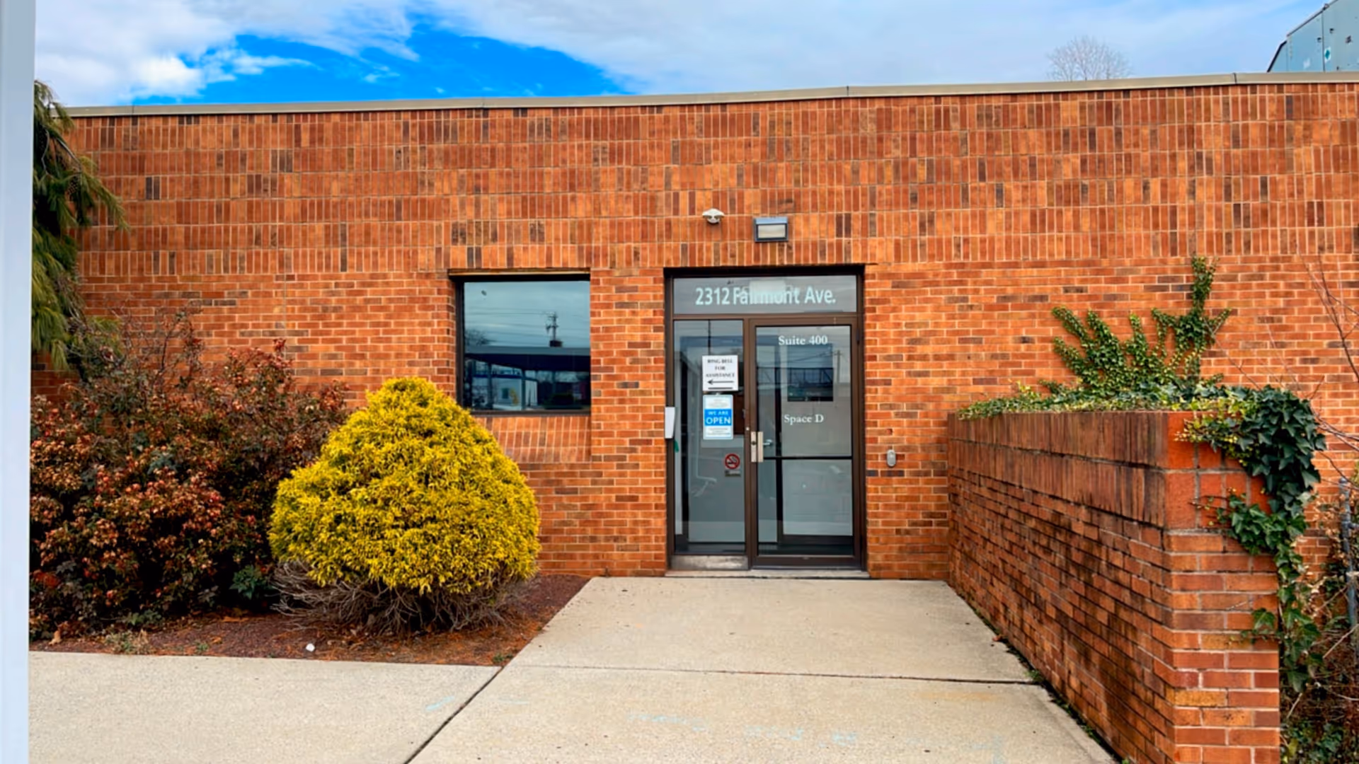 Brick building exterior with glass entrance and trimmed shrubs outside Premium Health Home Care Services.