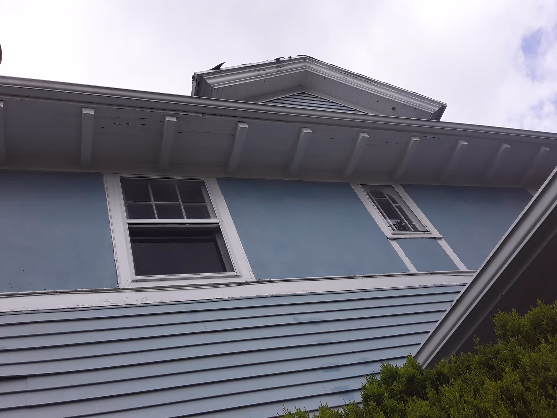 Blue two-story building exterior with white-trimmed windows and a gabled roof.