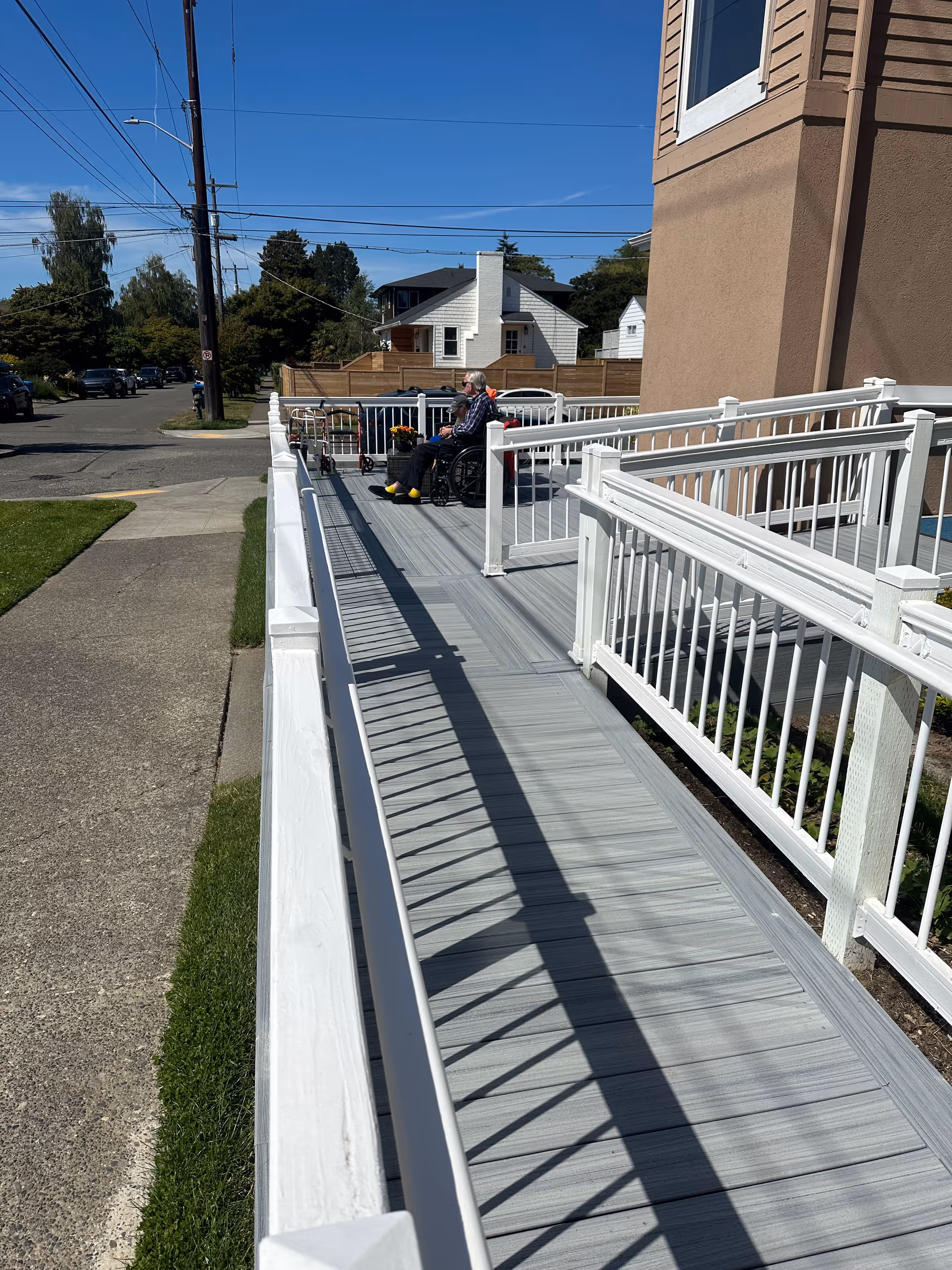 Elderly person in a wheelchair on a ramp outside Seaview AFH with white railings.