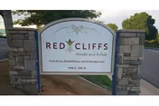 Stone-framed sign for Red Cliffs Health and Rehab at the facility entrance.