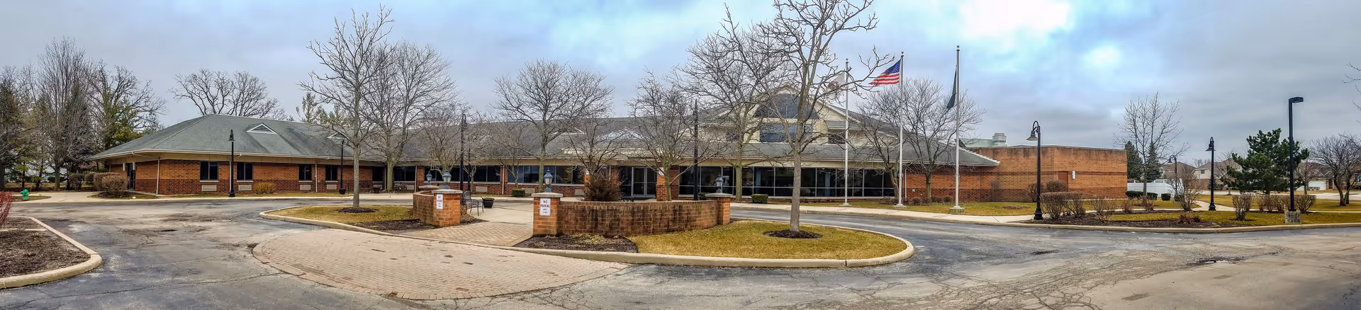 Exterior view of Lemont Nursing and Rehabilitation Center with brick building, circular driveway, and flagpoles.