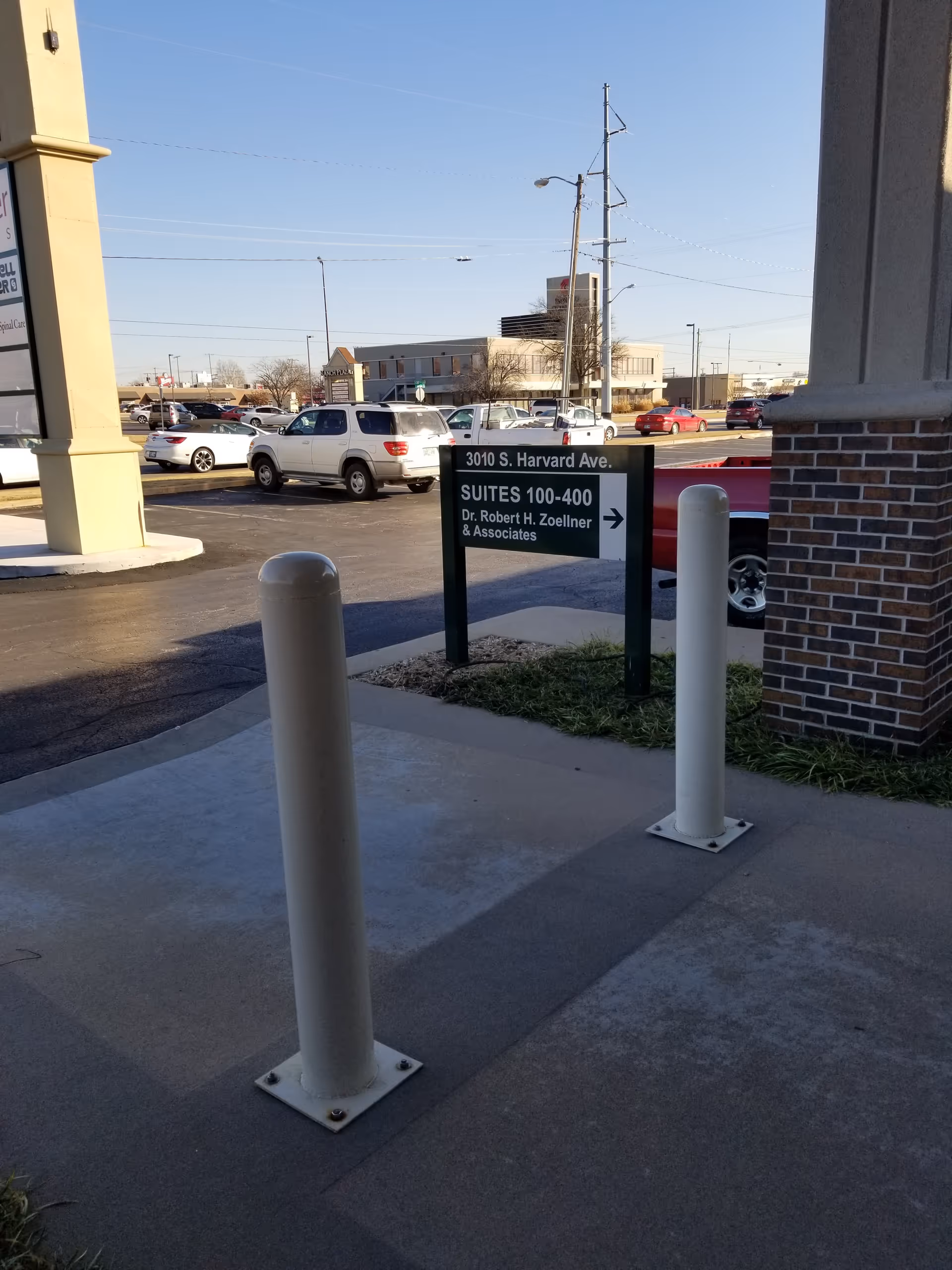 Exterior view of a building entrance with a sign and parked cars.