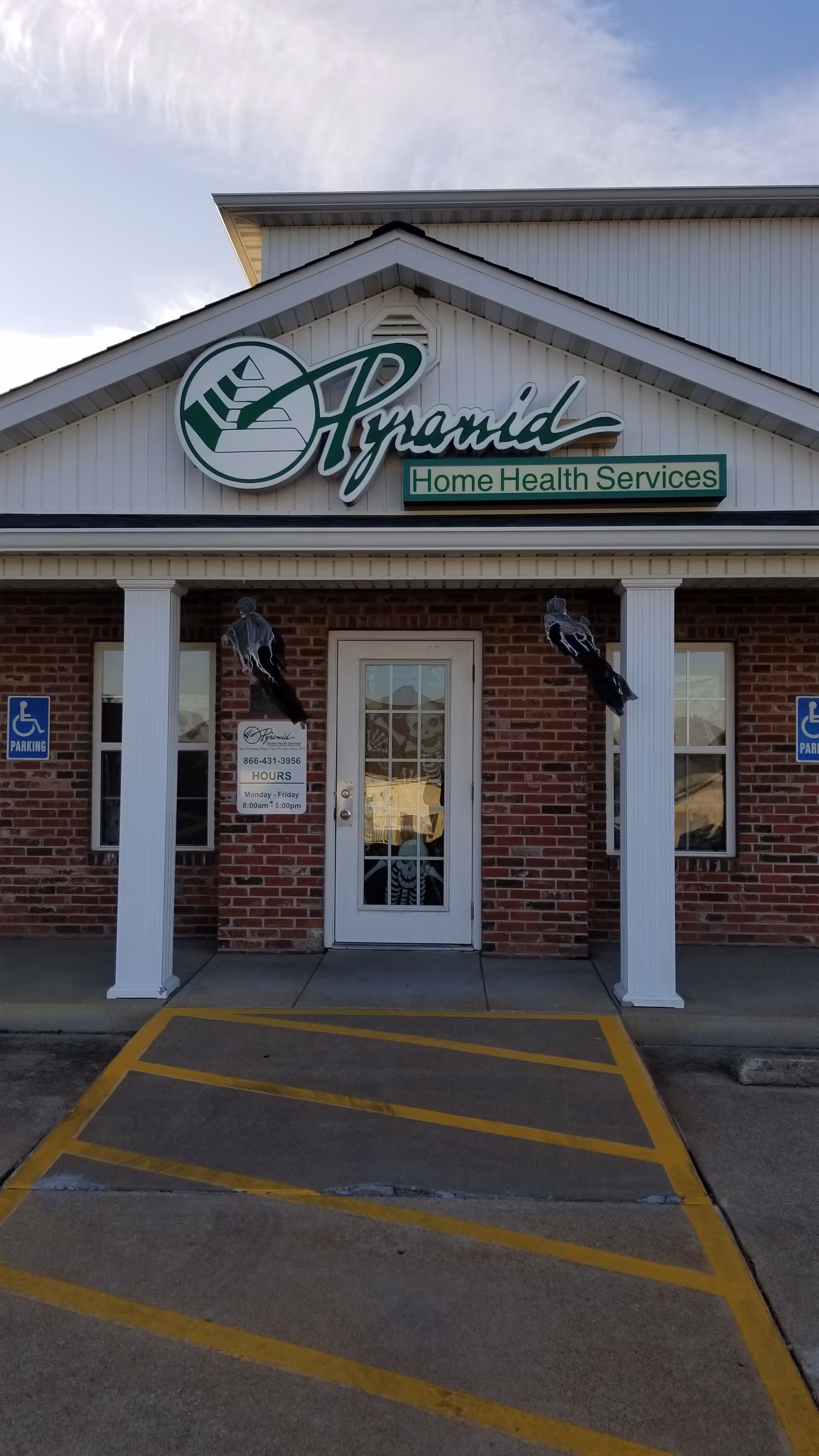 Brick facility exterior with Pyramid Home Health Services sign and accessible parking at entrance.