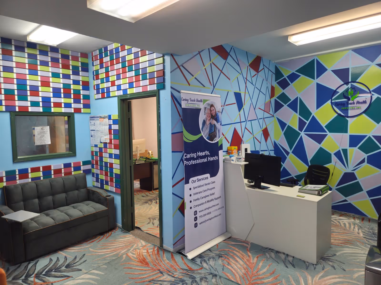 Colorful geometric walls surround a reception desk in a senior living facility lobby.