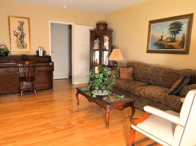 Cozy Magnolia Gardens living room with sofa, coffee table, piano, and artwork.
