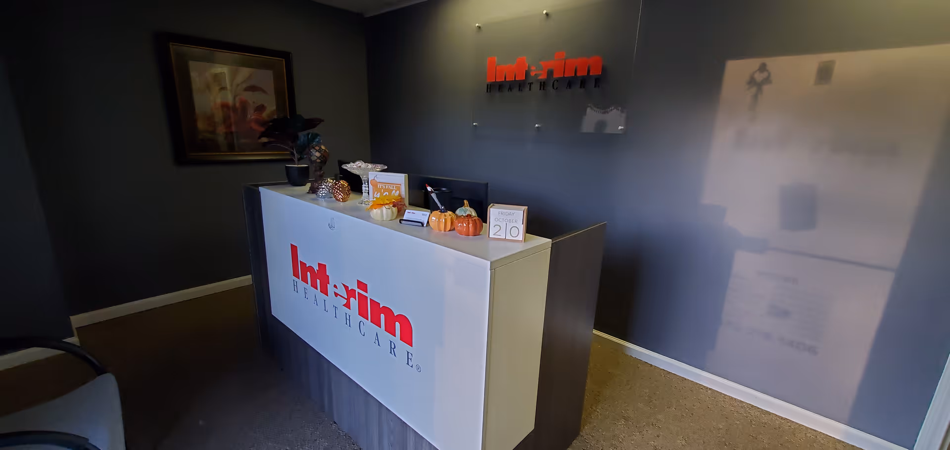 Reception desk in a lobby of Interim HealthCare of Gainesville with logo on the wall.