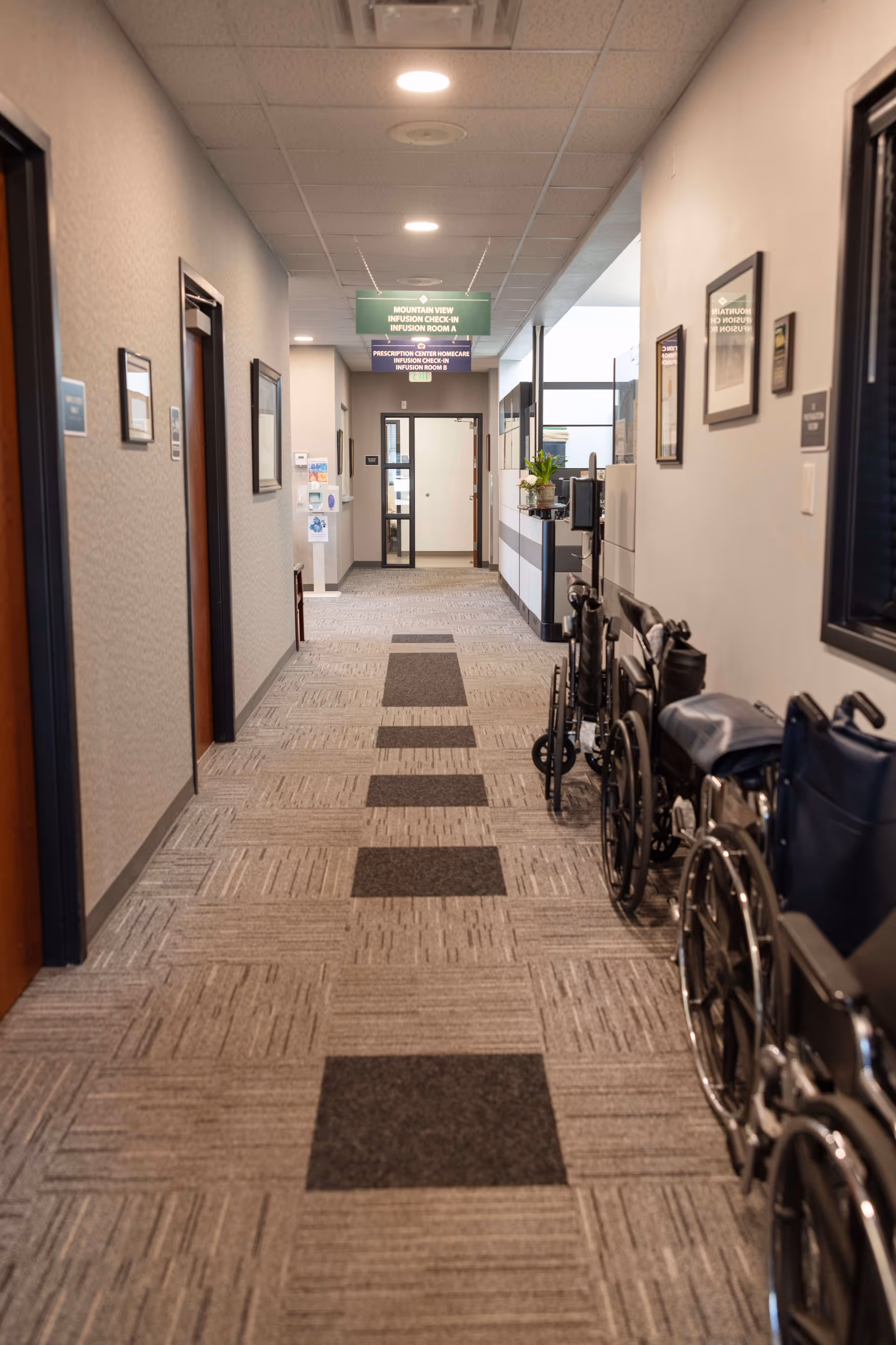 A long interior hallway in a senior care facility with wheelchairs along the right.