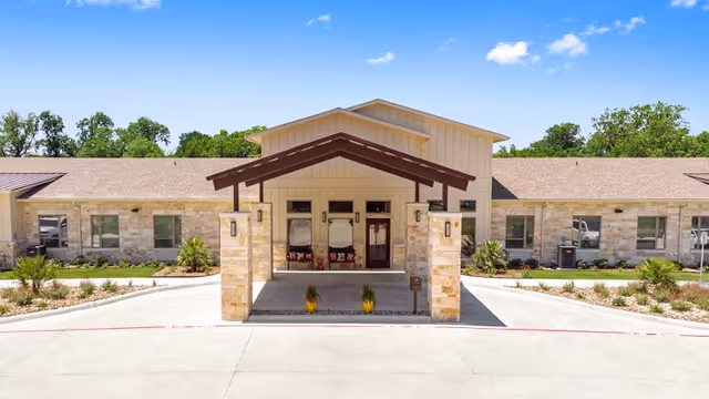 Single-story assisted living facility exterior with a stone entrance and covered entryway.