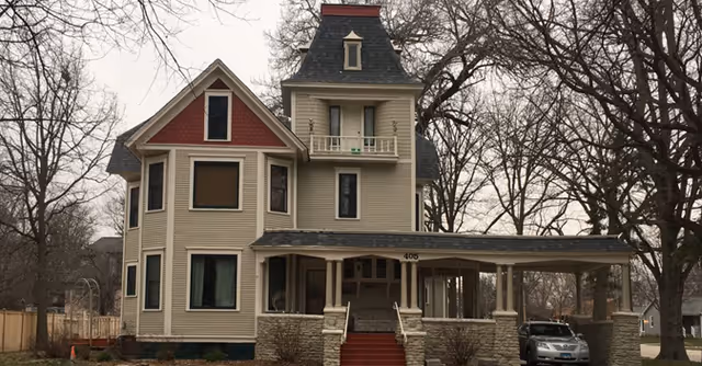 Exterior view of a Victorian-style senior living facility with a large front porch.