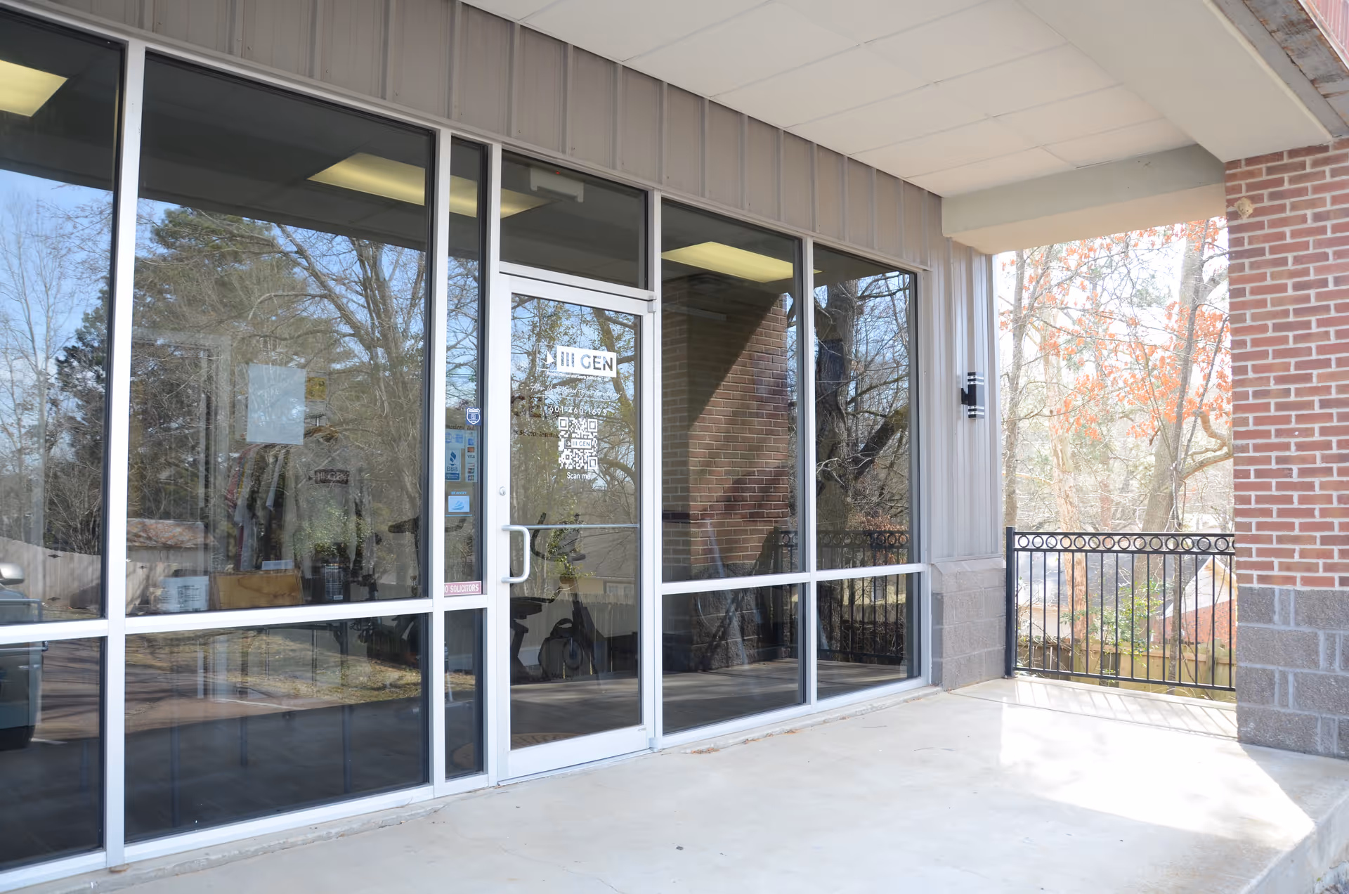Glass storefront entrance of a senior facility with brick exterior and railing.
