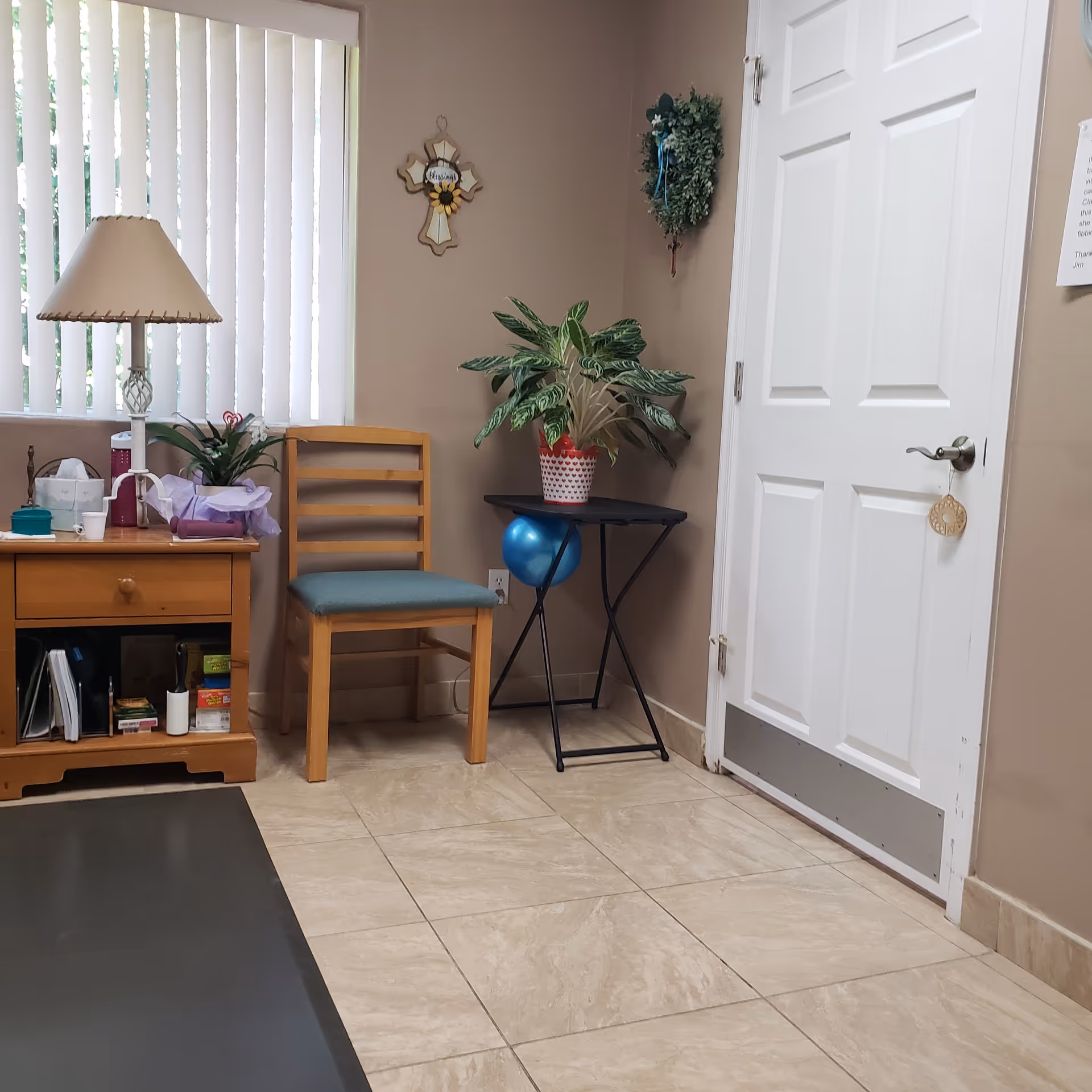 Interior entry area with a chair, small table, potted plant, lamp, and doorway.