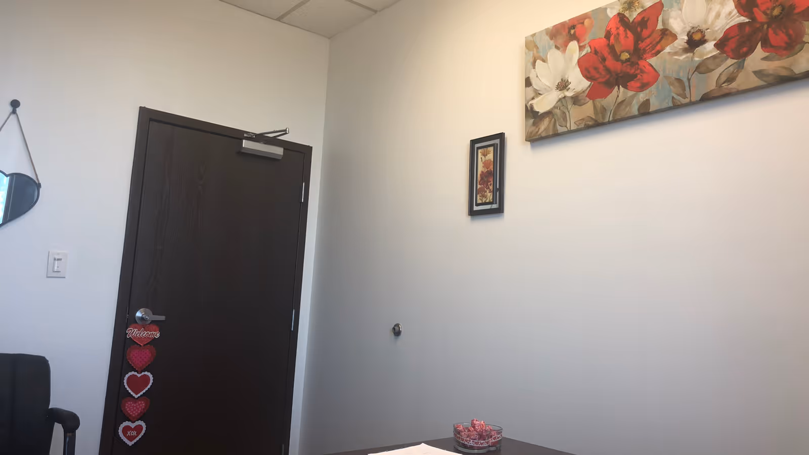 Interior room with a dark door, wall decor, and a pink bowl on a small table.