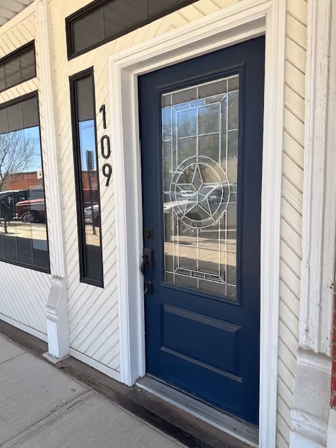 Blue front door with decorative glass, white siding, and vertical address numbers 109.