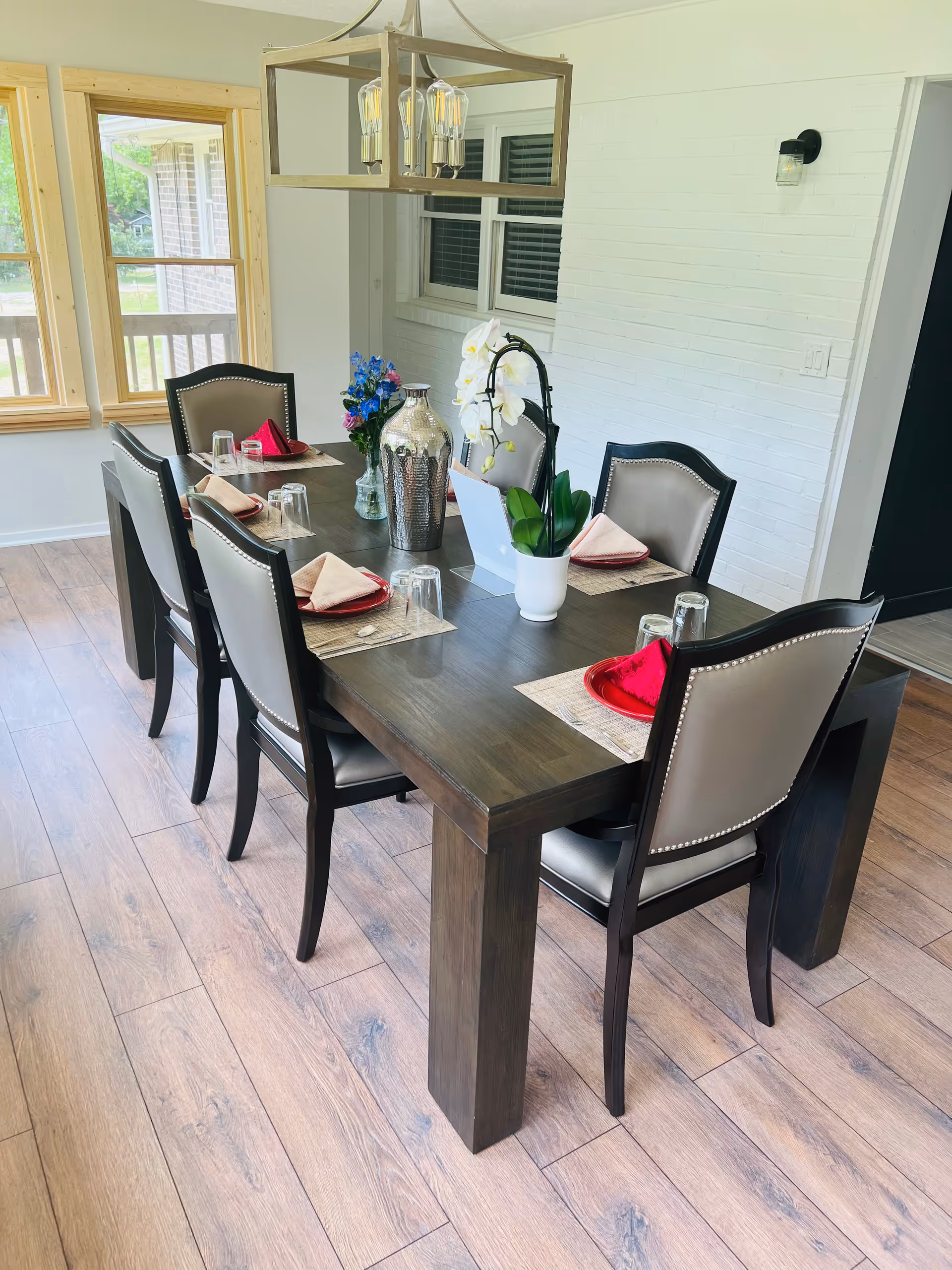 A six seat dining room table set with placemats, napkins, glassware, and a centerpiece.