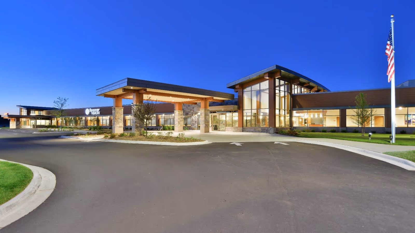 Modern Spooner Health senior living facility exterior with glass entrance and flag.