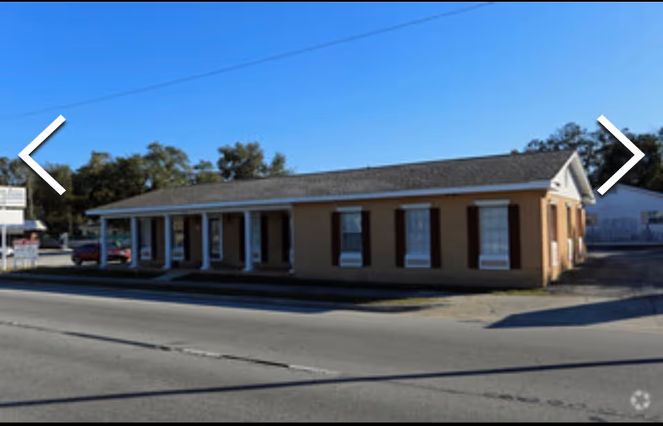 Single-story beige senior living facility exterior with a columned front along the street.