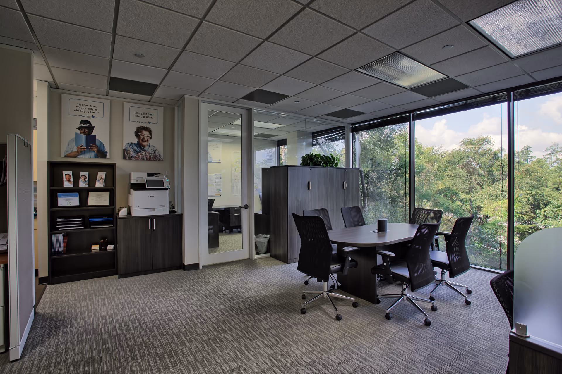 Office conference room with large windows, a conference table, and black chairs.