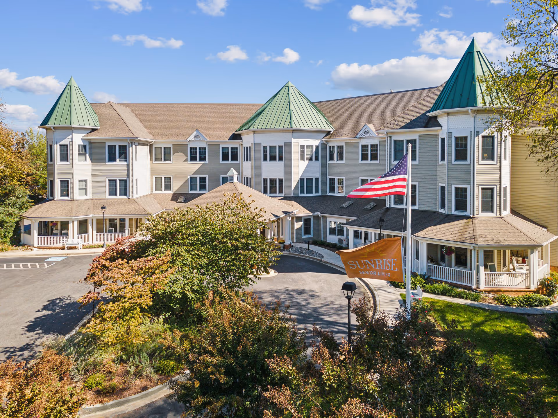 Exterior view of Sunrise Senior Living facility with flag, sign, and turreted corners.