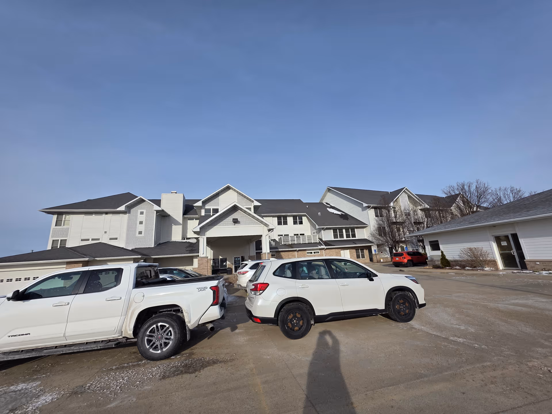 Exterior view of The Lakeside Village senior living facility with parked vehicles.
