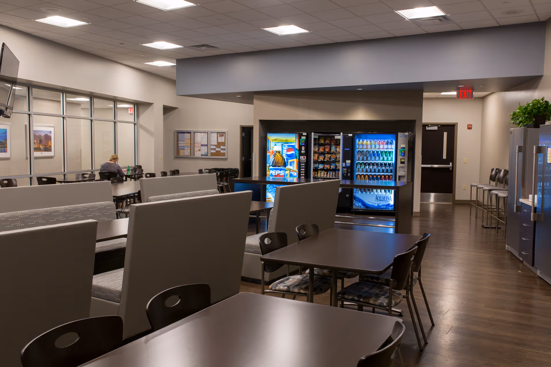 Indoor senior living common area with tables, seating, and vending machines.