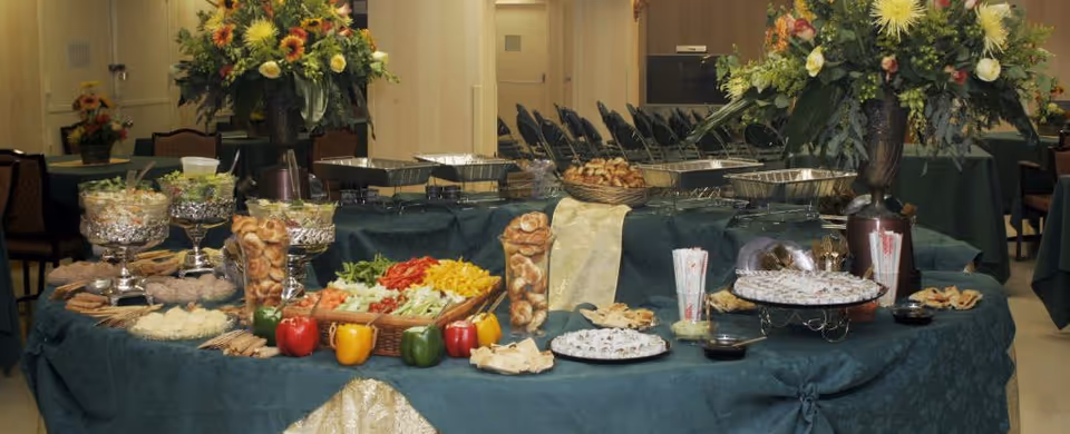 A long buffet table with assorted dishes and floral centerpieces in a dining room.
