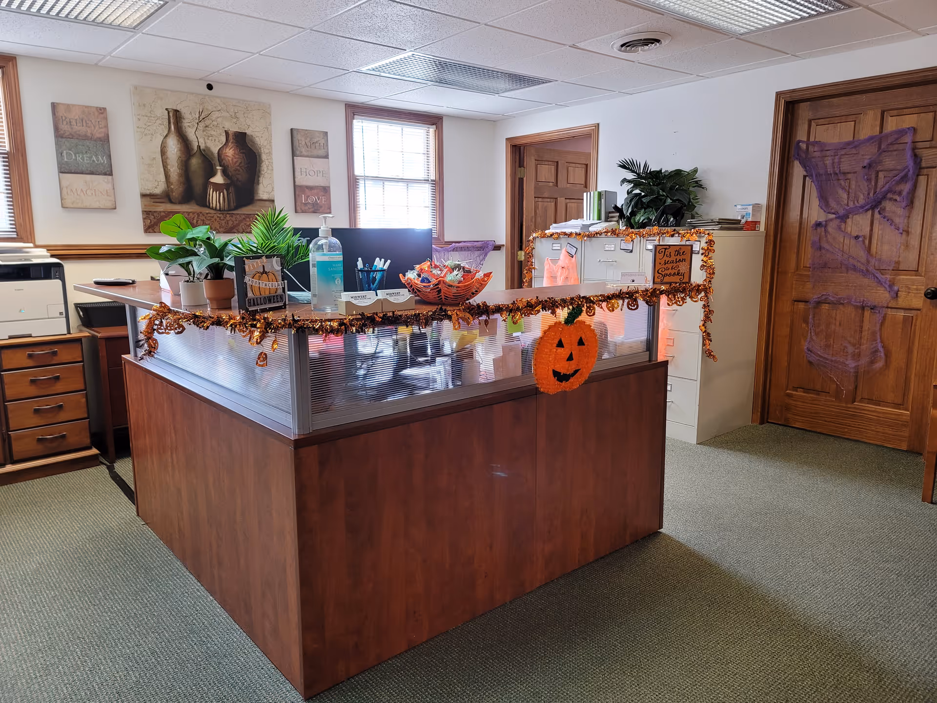 Office front desk decorated for Halloween with pumpkins and garlands inside a senior facility.