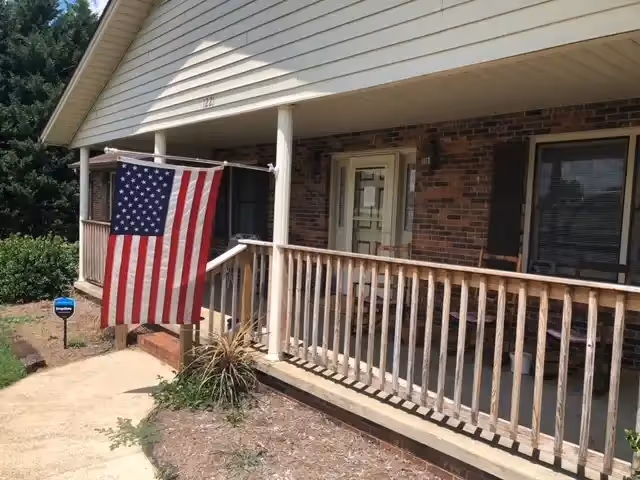 Front view of TLC Family Care Home, LLC, brick exterior with a porch and American flag.