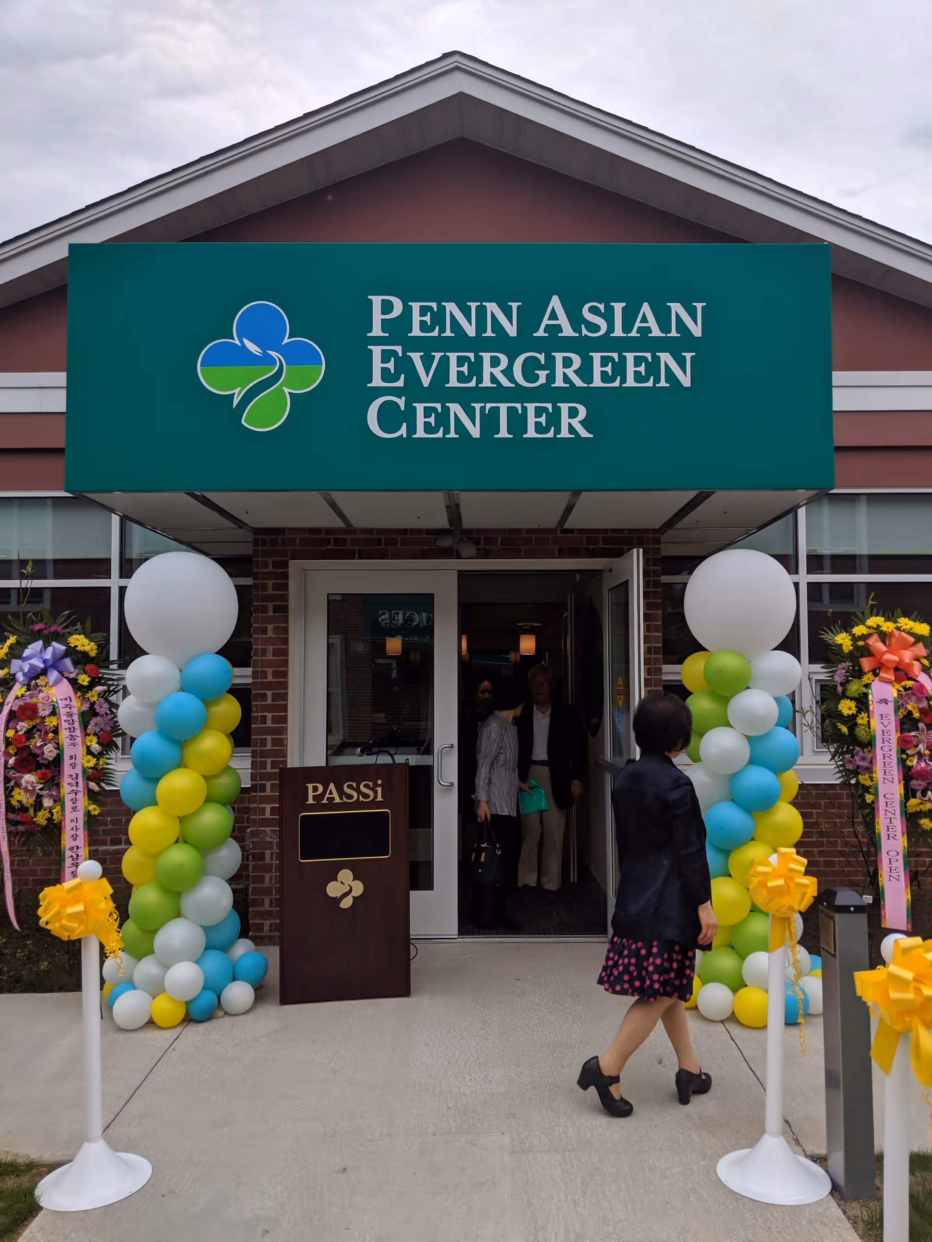 Green PASSi sign over the Penn Asian Evergreen Center entrance with balloons.