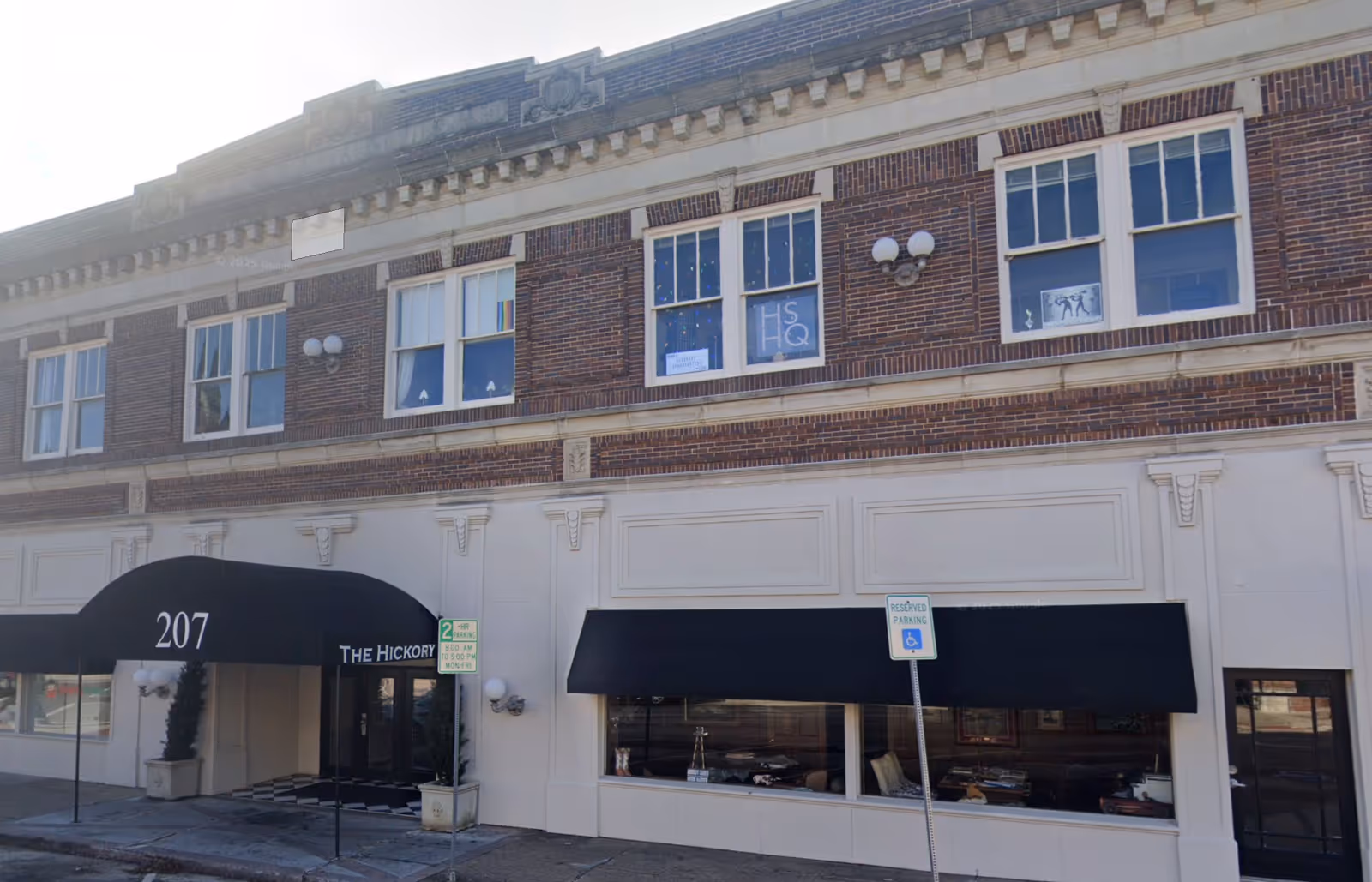 A brick building facade features black awnings and a storefront entrance.