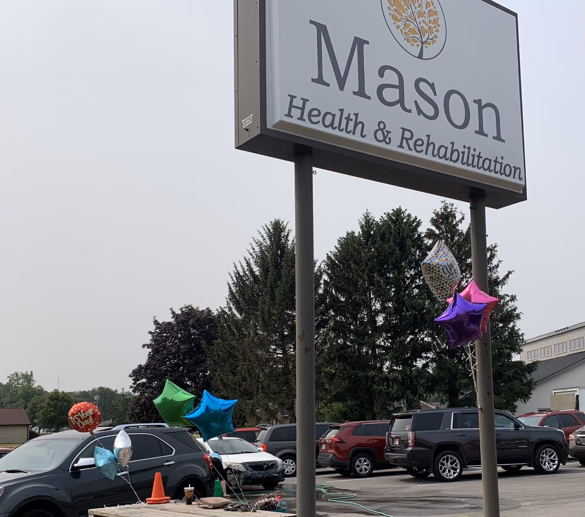 Front exterior of Mason Health & Rehabilitation with balloons and parked cars