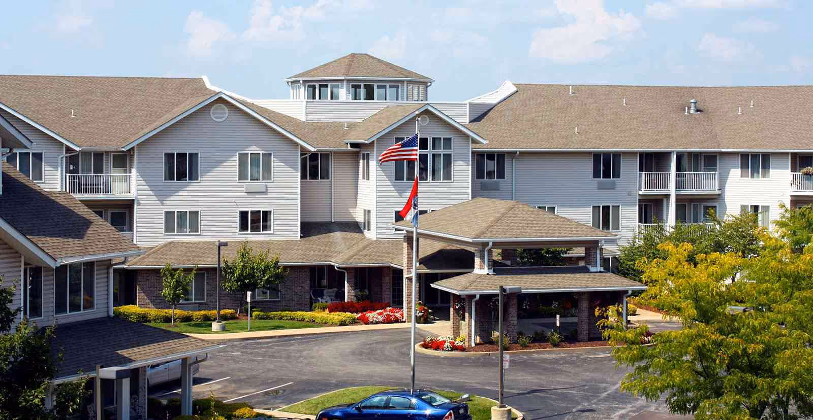 Exterior view of Solstice Senior Living at Fenton with flagpoles and an entry canopy.