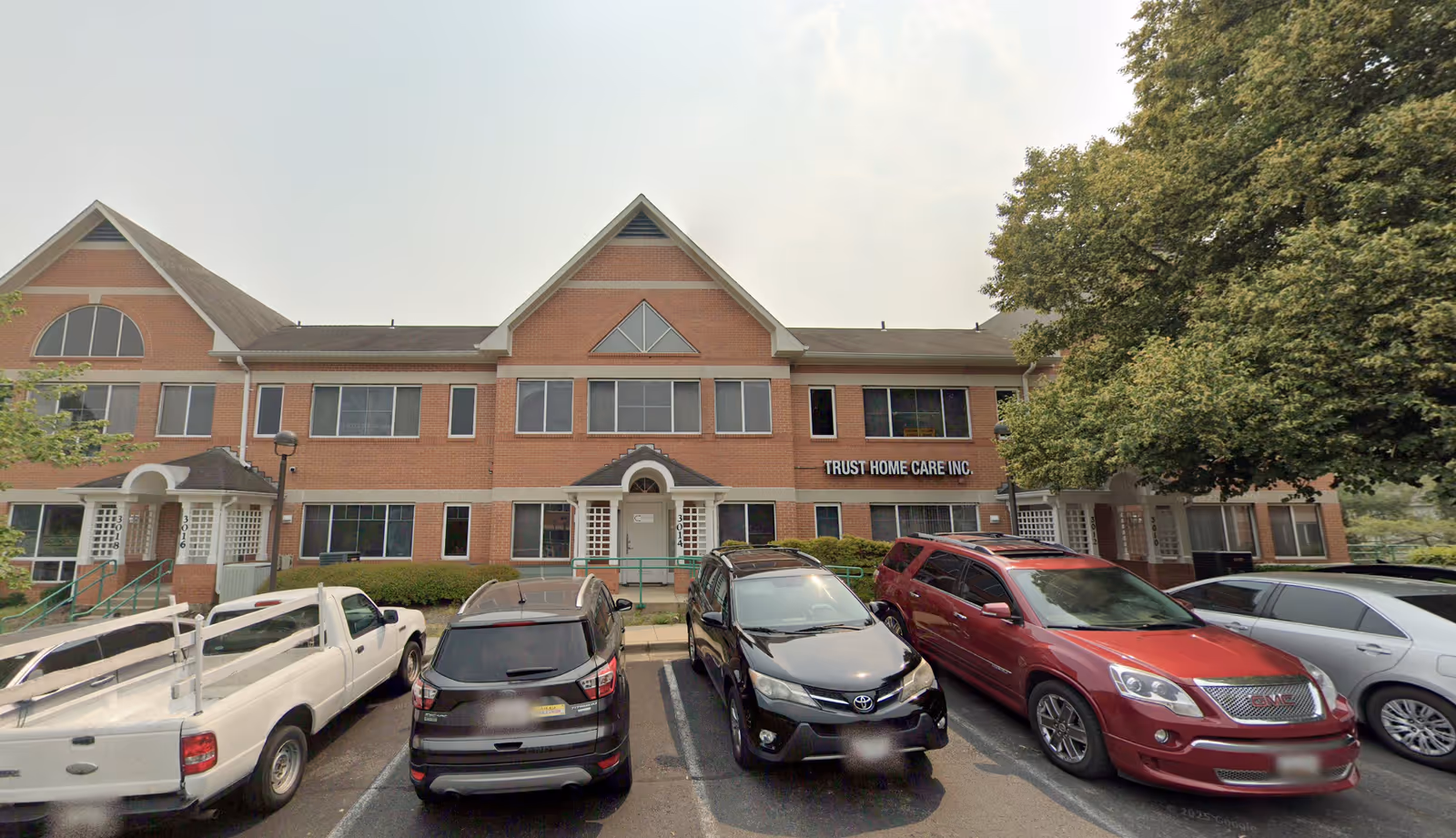 Brick senior care facility front with parked cars and a Trust Home Care Inc. sign.