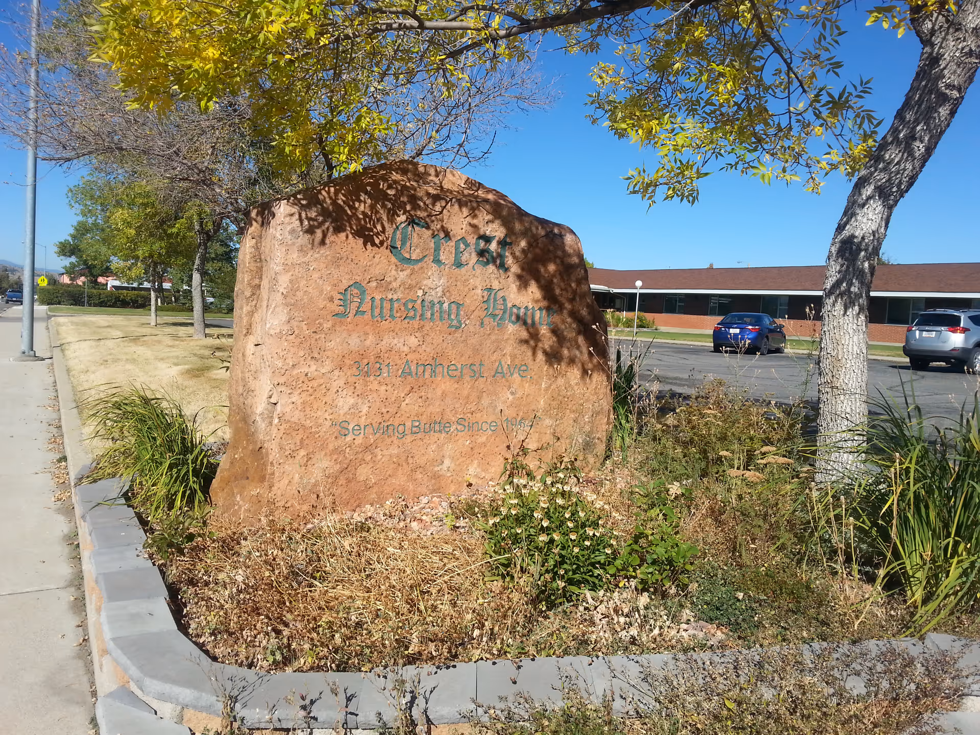 A large rock sign reading Crest Nursing Home sits in a landscaped front yard.