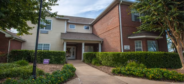 Exterior view of Brookdale Spring Shadows building with a landscaped front entrance and walkway.