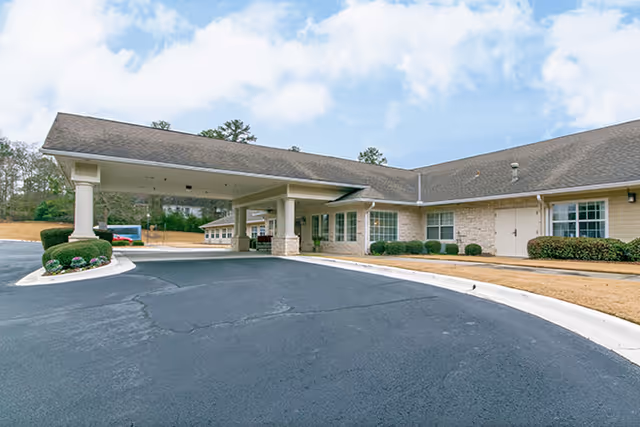 A curved driveway leads to a single story senior living facility with a covered entrance.