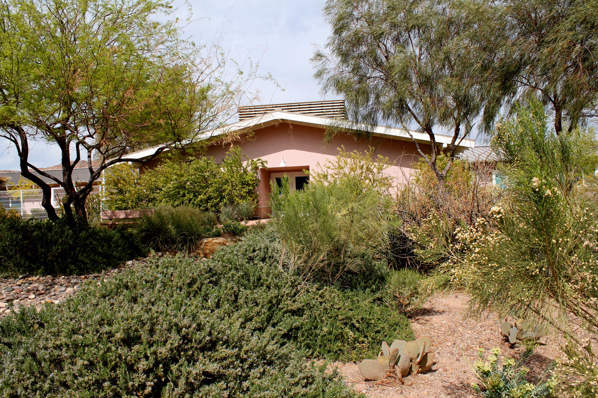 Front view of Nevada State Veterans Home, a single-story pink building with desert landscaping.