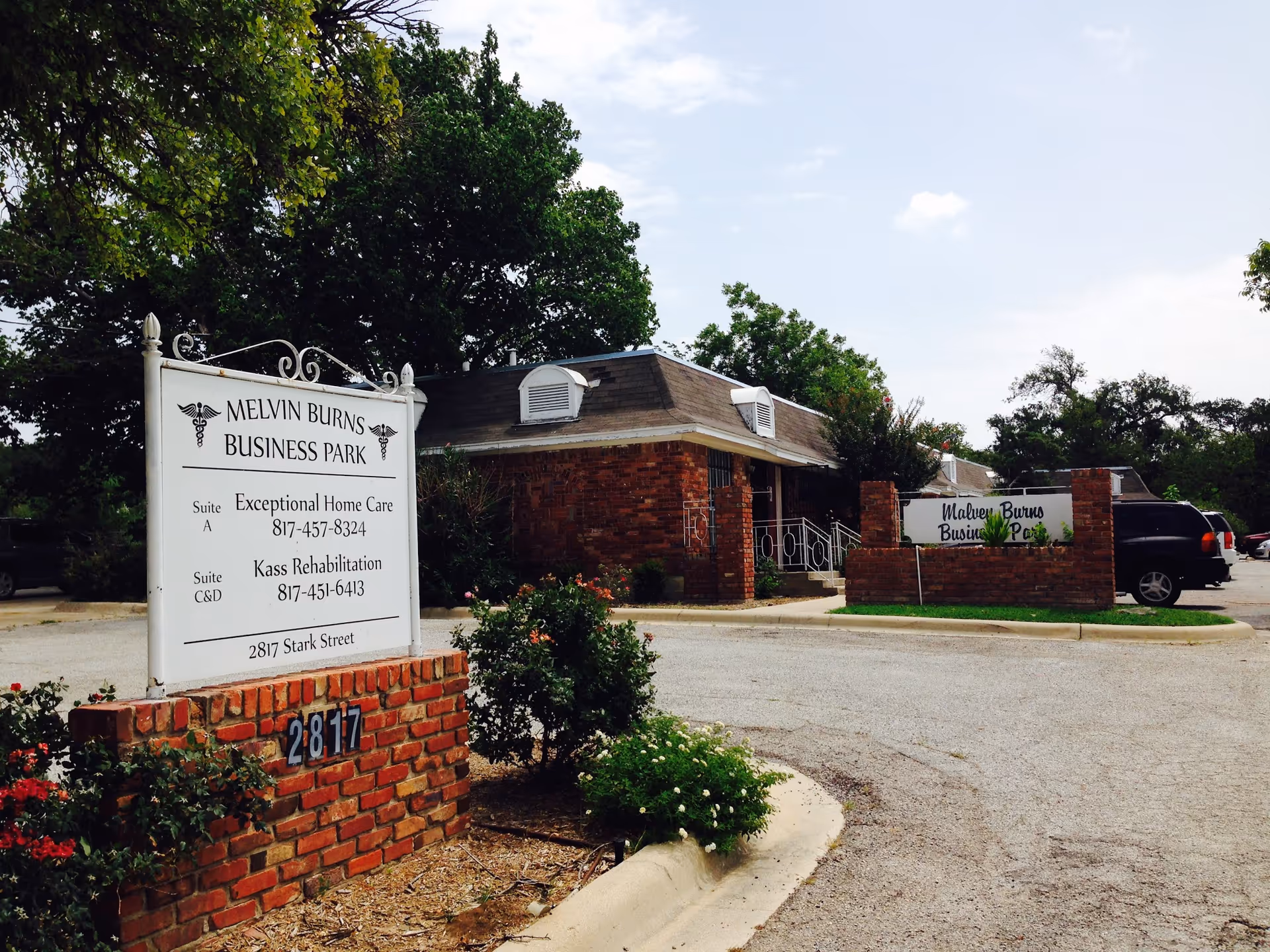 Exterior of a brick building with a sign for Exceptional Home Care and parking.