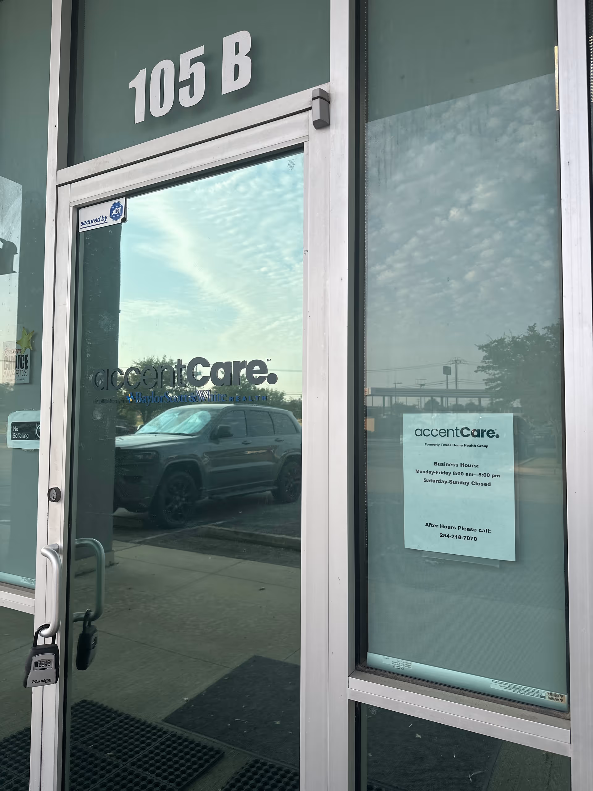 Exterior glass door entrance with 105 B and accentCare logo; car reflected outside.