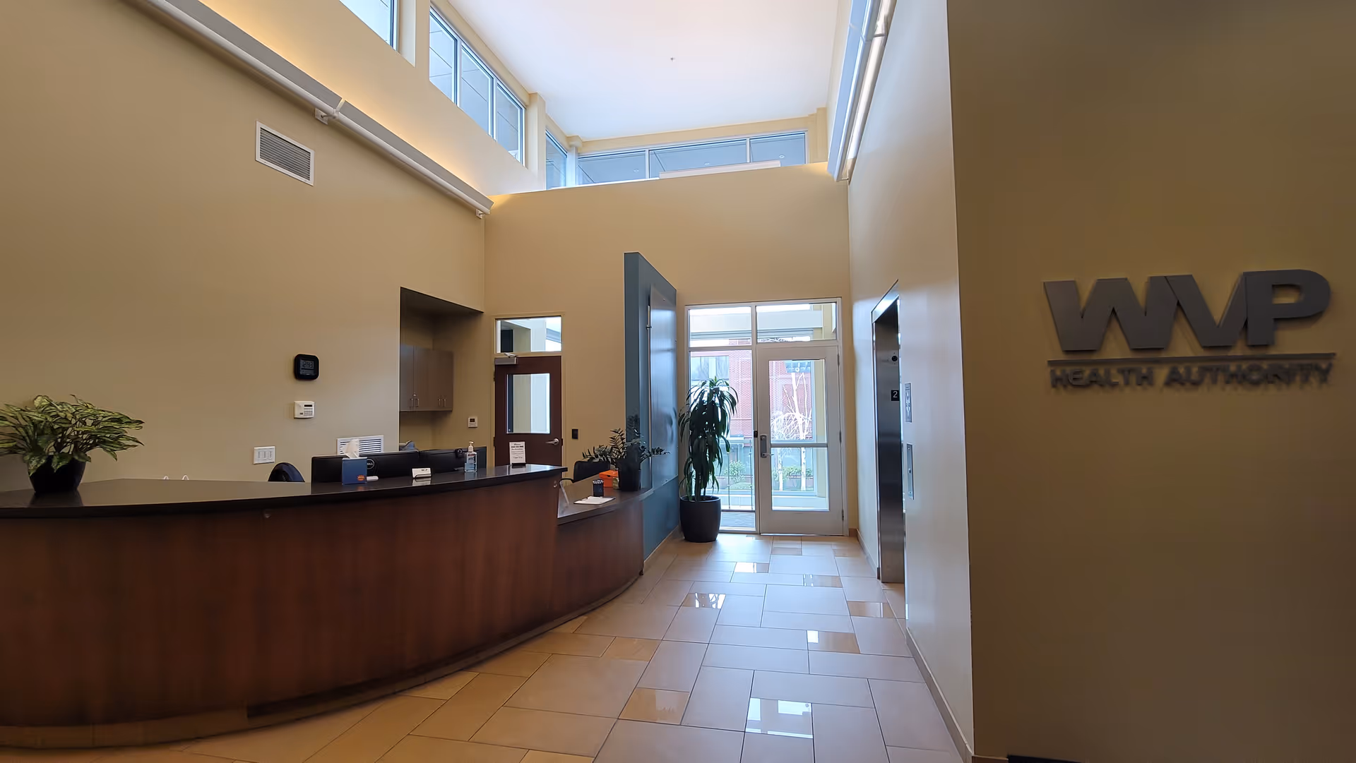 Bright interior lobby with curved reception desk and glass entry doors.