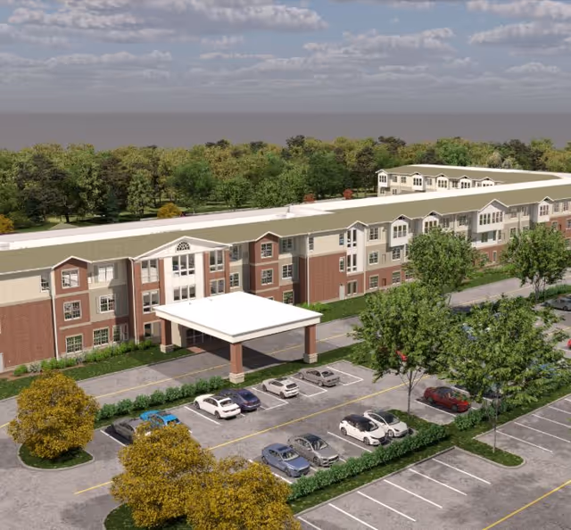 Exterior view of a large senior living facility with a covered entrance and parking.